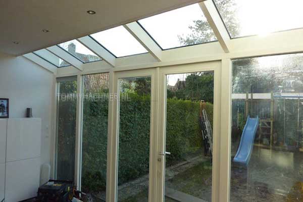Aanbouw met stukje plat dak en een schuin gedeelte met glazen dak kozijn is uitgevoerd in hardhout