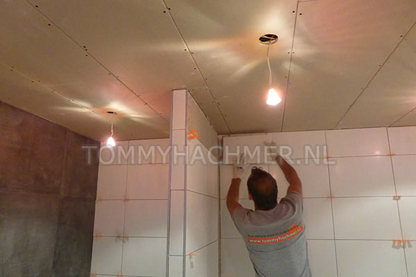 Badkamer met Douche muurtje als afscheiding vloertegels lopen op een muur door