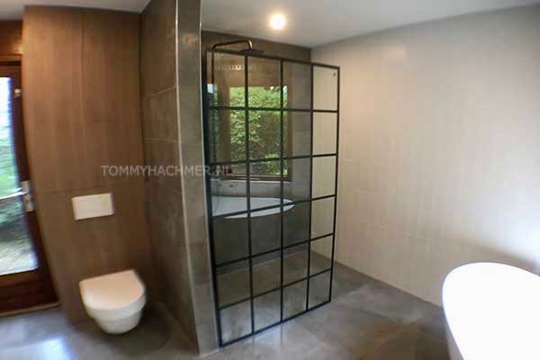 Badkamer met zwart glazen douchescherm zwarte kranen en douche garnituur vrijstaand kunststof bad zonder pootjes slaapkamer wordt badkamer